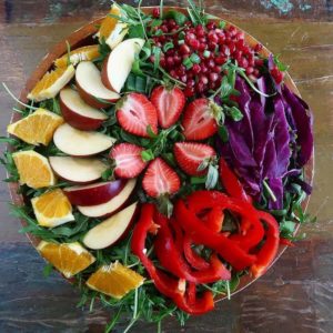 colorful arugula salad with oranges, apples, strawberries, bell peppers and pomegranates