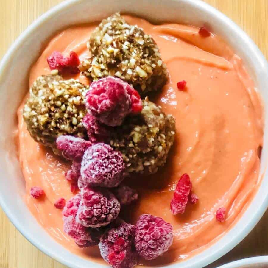 pink smoothie bowl topped with raspberries and granola